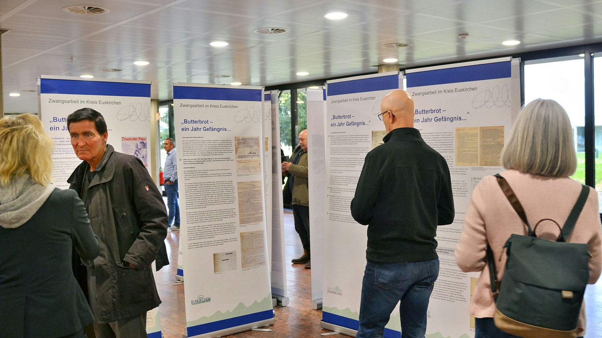 Besucher der Ausstellung stehen vor den Infotafeln.