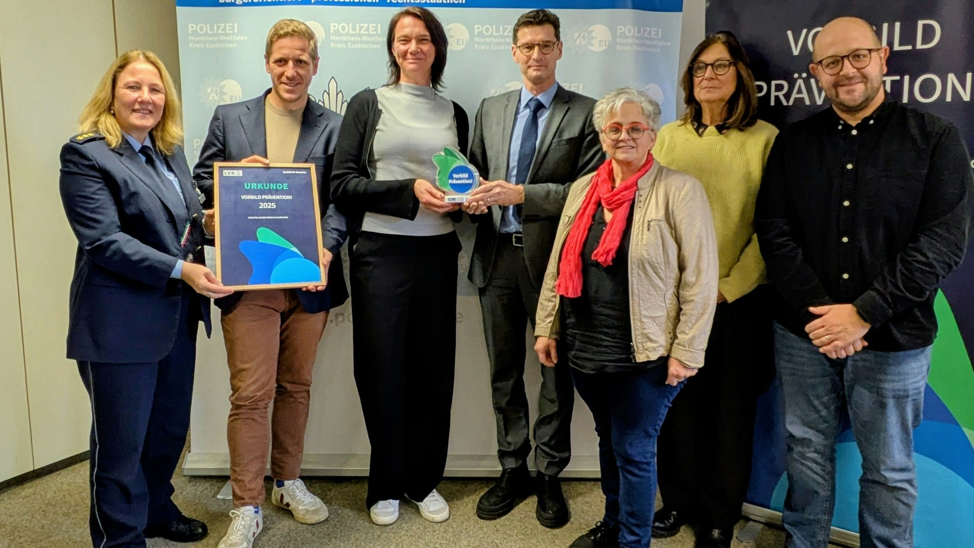 Auf einem Gruppenfoto präsentieren die Beteiligten die Trophäe und die Urkunde.