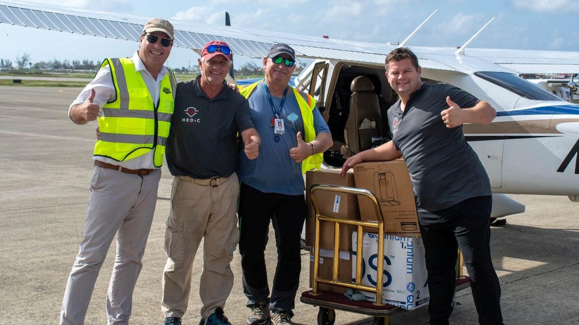 Vier Männer stehen auf einem Rollfeld vor einem kleinen Flugzeug.