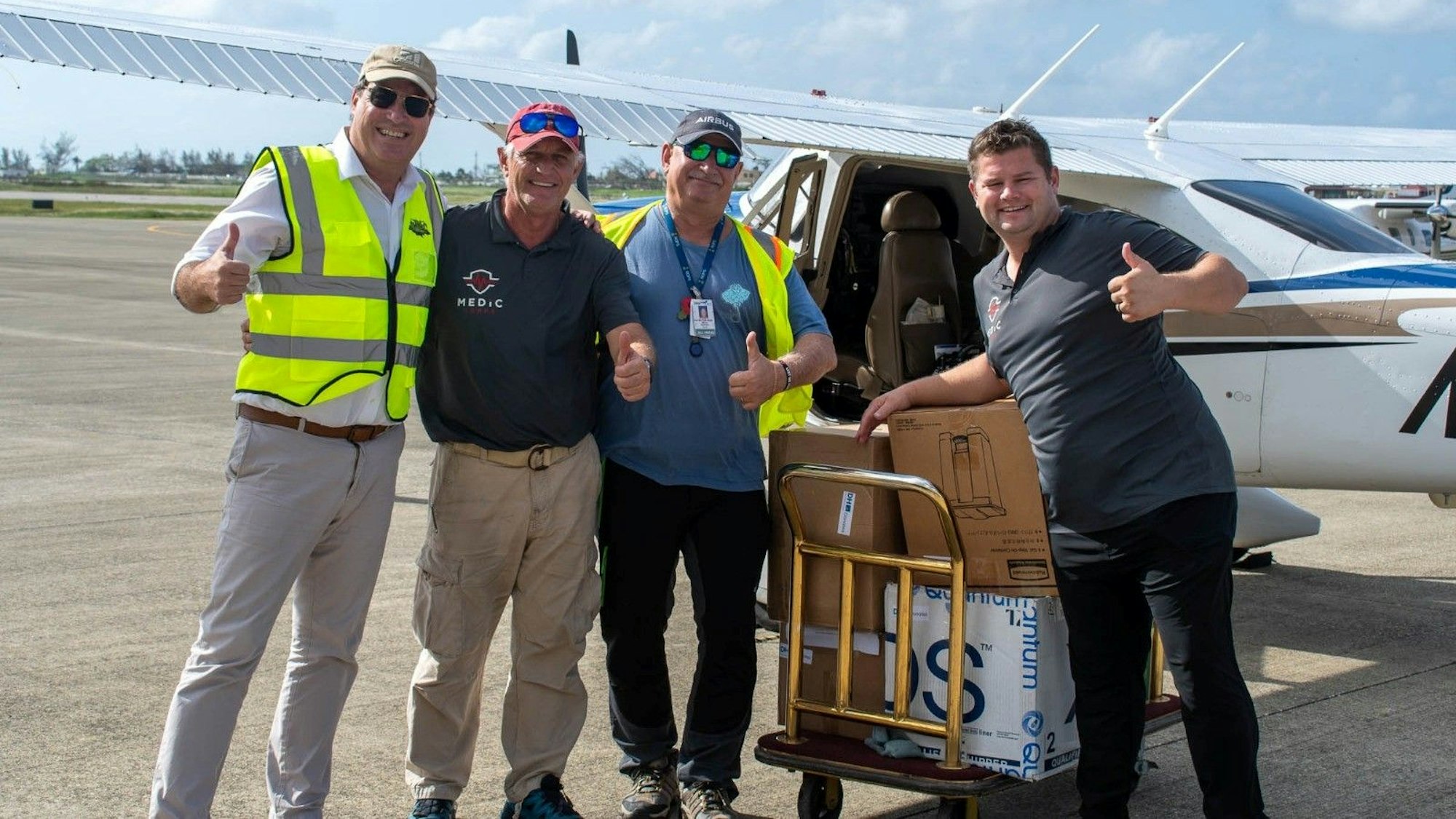 Vier Männer stehen auf einem Rollfeld vor einem kleinen Flugzeug.