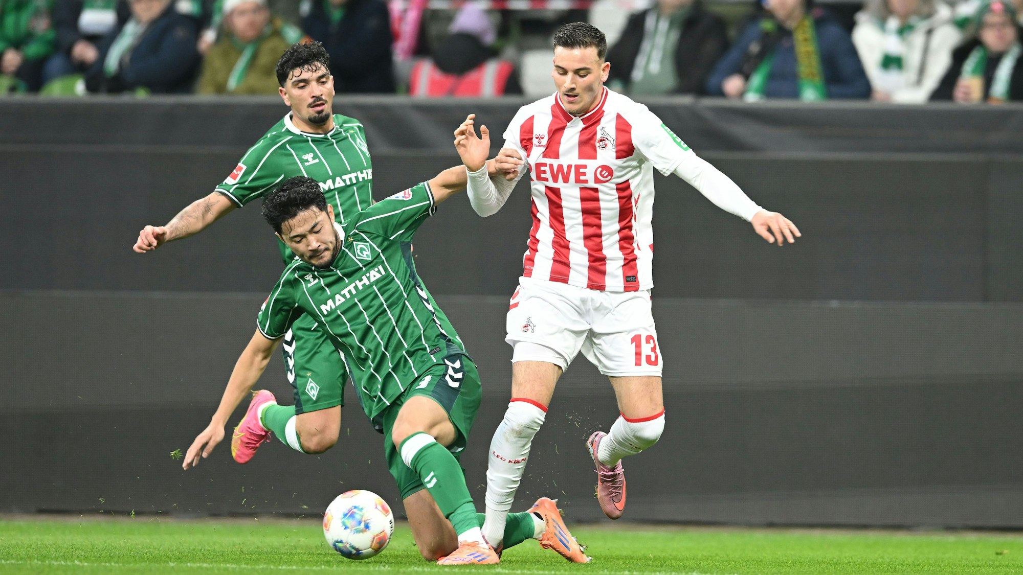 29.11.2025, Bremen: Fußball: Bundesliga, Werder Bremen - 1. FC Köln, 12. Spieltag, im Weserstadion. Cameron Puertas Castro (l) und Yukinara Sugawara (M) eide Werder Bremen) kämpfen gegen Saïd El Mala (1. FC Köln) um den Ball.