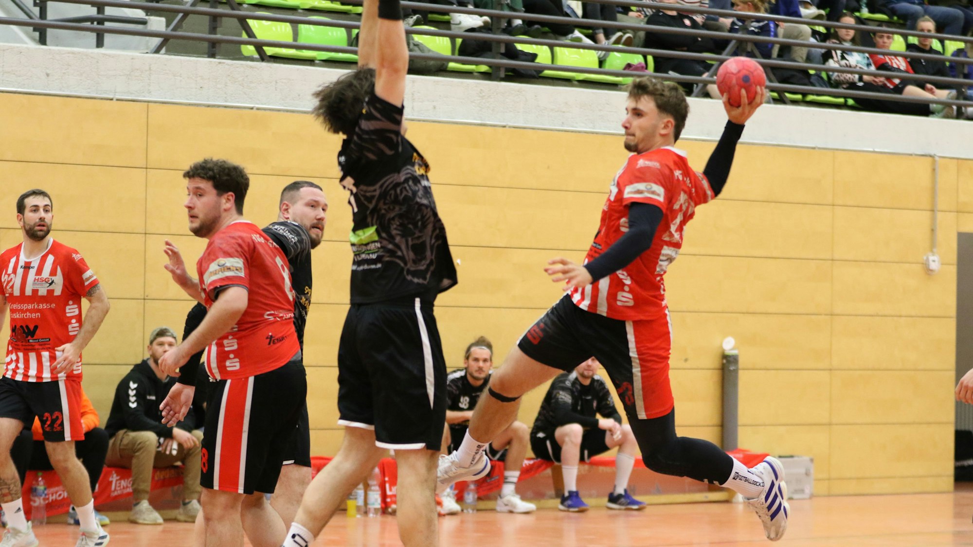 Schreiber ist zum Sprungwurf hochgestiegen. Ein Abwehrspieler versucht, den Ball zu blocken.