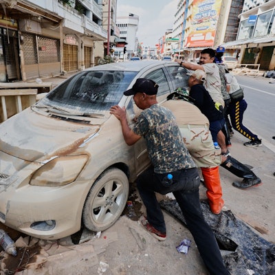Menschen bewegen ein von den Überschwemmungen beschädigtes Auto in der Provinz Songkhla im Süden Thailands.