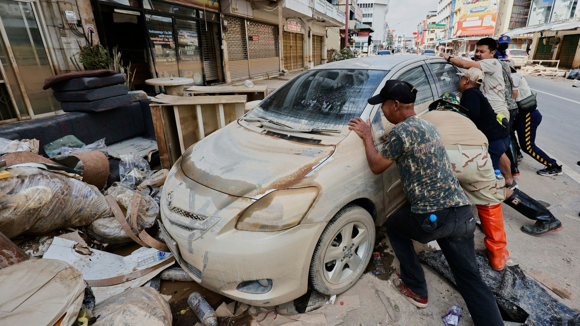 Menschen bewegen ein von den Überschwemmungen beschädigtes Auto in der Provinz Songkhla im Süden Thailands.