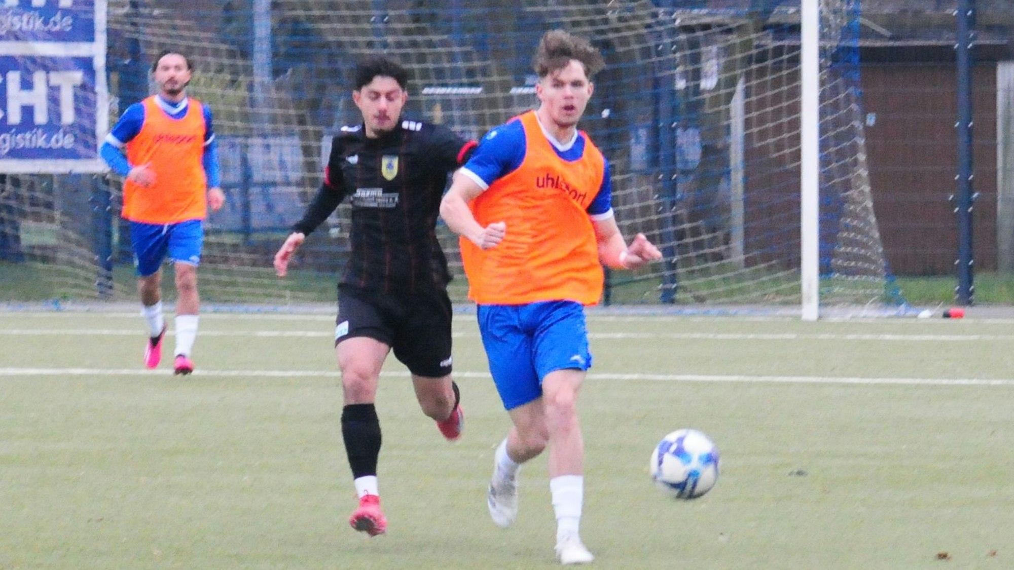 Das Foto zeigt einen Königsdorfer Spieler, im orangefarbenen Leibchen, der seinen Dürener Gegenspieler hinter sich lässt.