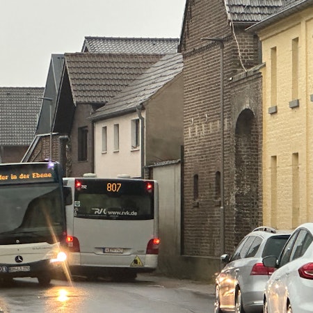 Zwei Busse fahren auf einer schmalen Straße aneinander vorbei.