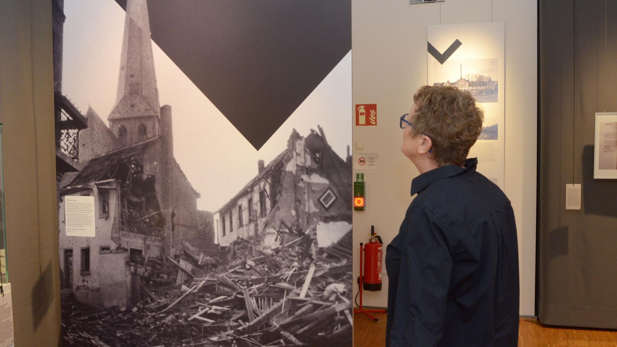 Eine Frau betrachtet ein großformatiges Foto, das die Zerstörung von Häusern in Euskirchen während des Zweiten Weltkrieges zeigt.