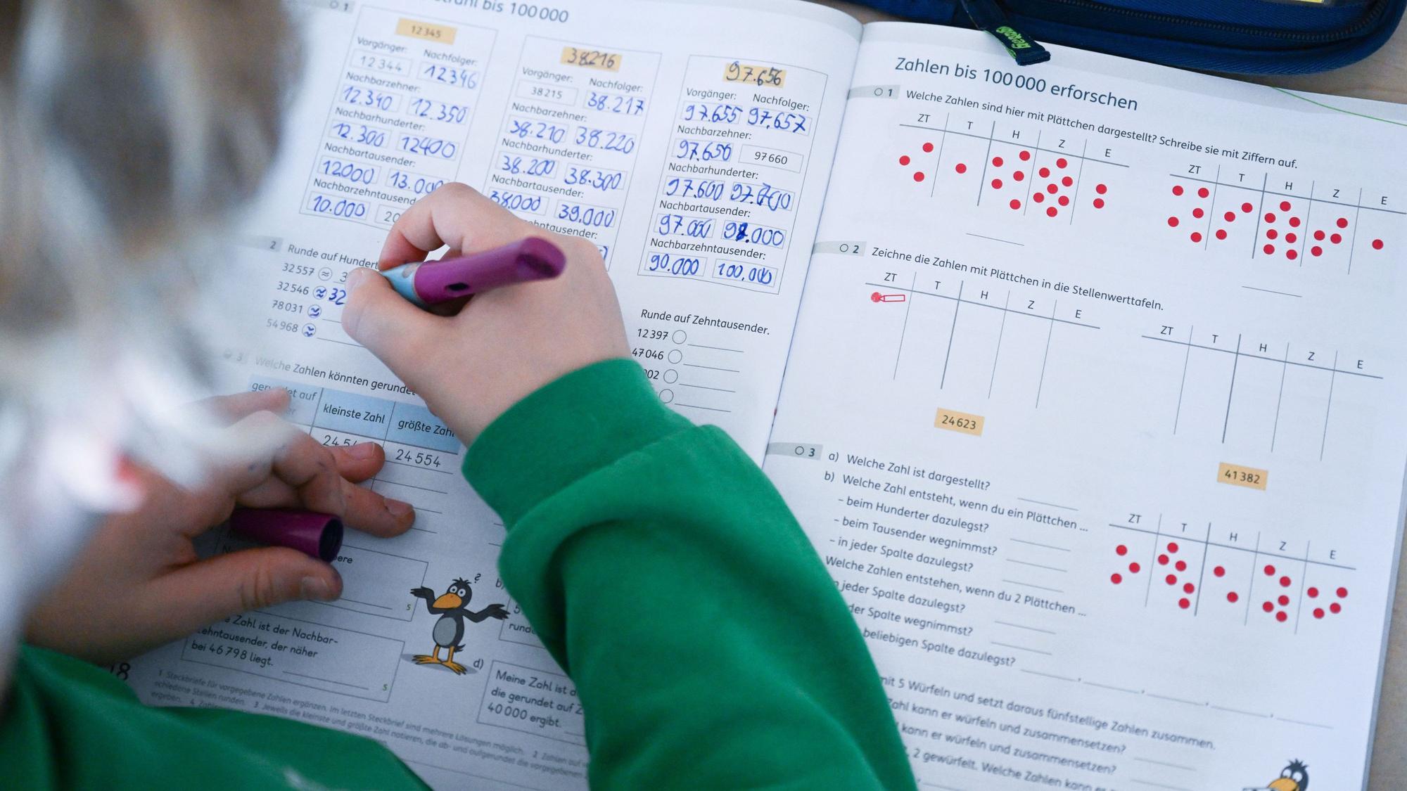 In einer Grundschule arbeitet ein Schüler einer vierten Klasse in einem Heft an seinen Mathematikaufgaben.