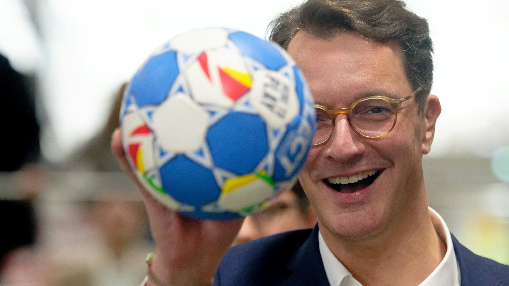 Hendrik Wüst (CDU), Ministerpräsident von Nordrhein-Westfalen deutet bei einer Pressekonferenz über Neuerungen des Bewerbungskonzepts für die olympischen und paralympischen Spiele einen Wurf mit einem Handball an.