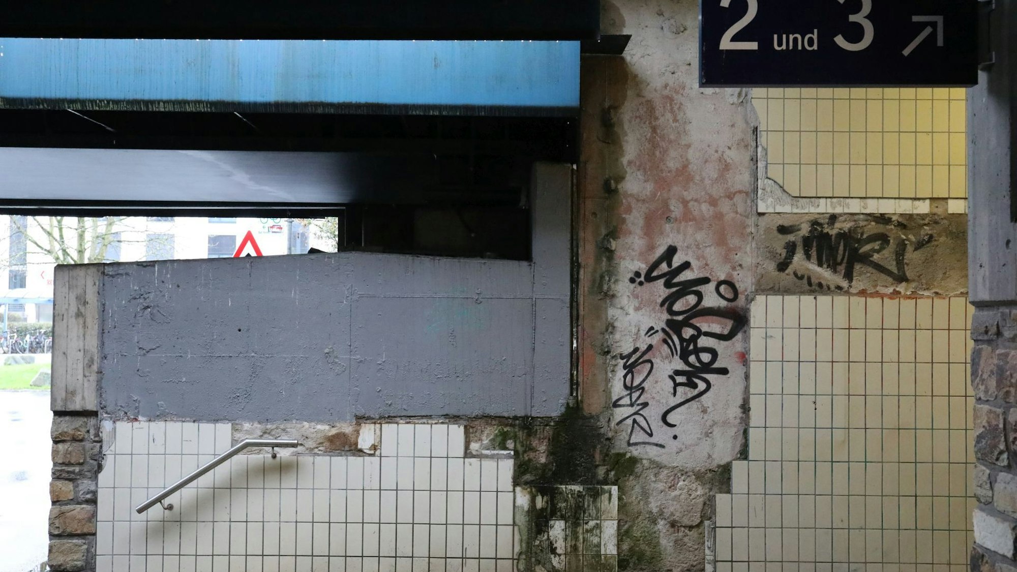 Ein hässlicher, gefliester und mit Graffiti versehener Aufgang zum Bahnhof.