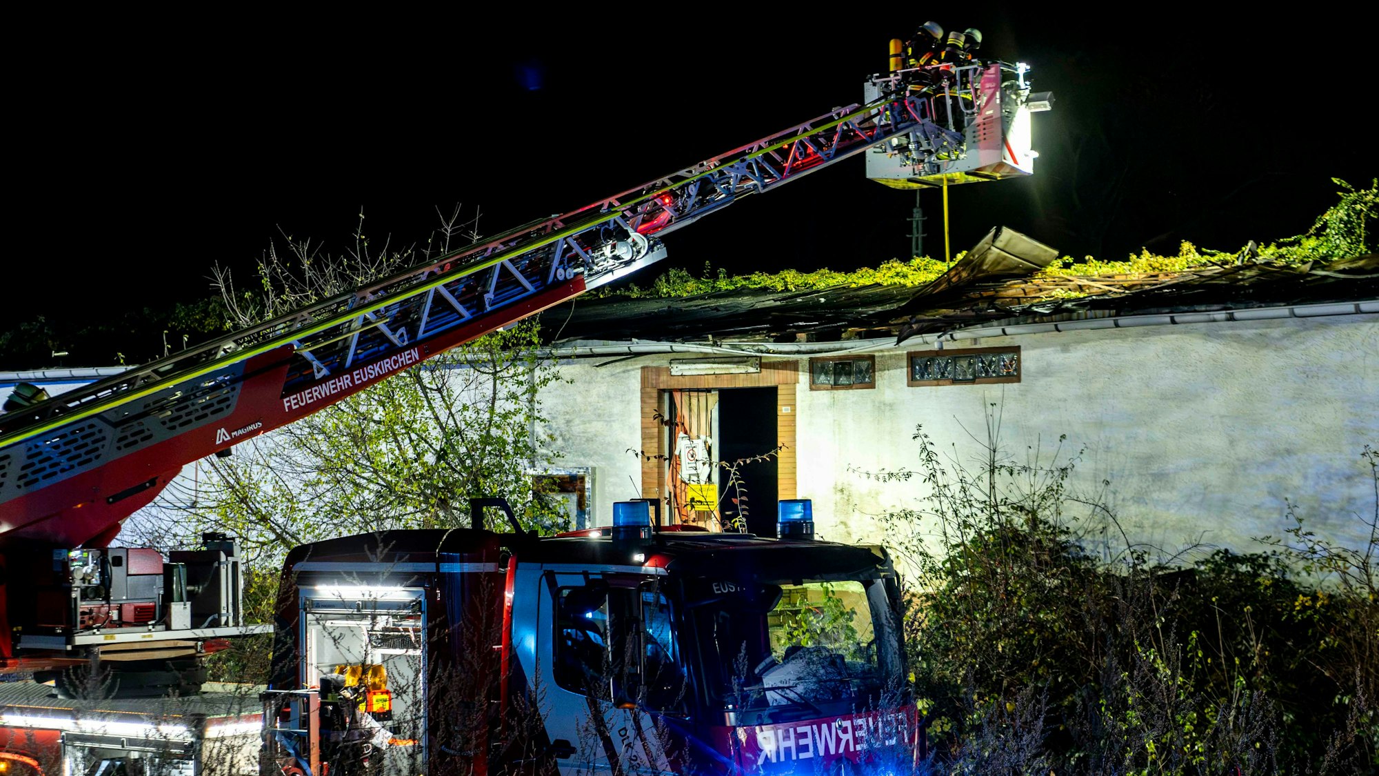Ein Feuerwehrauto steht vor einem Gebäude, die Drehleiter ist ausgefahren.