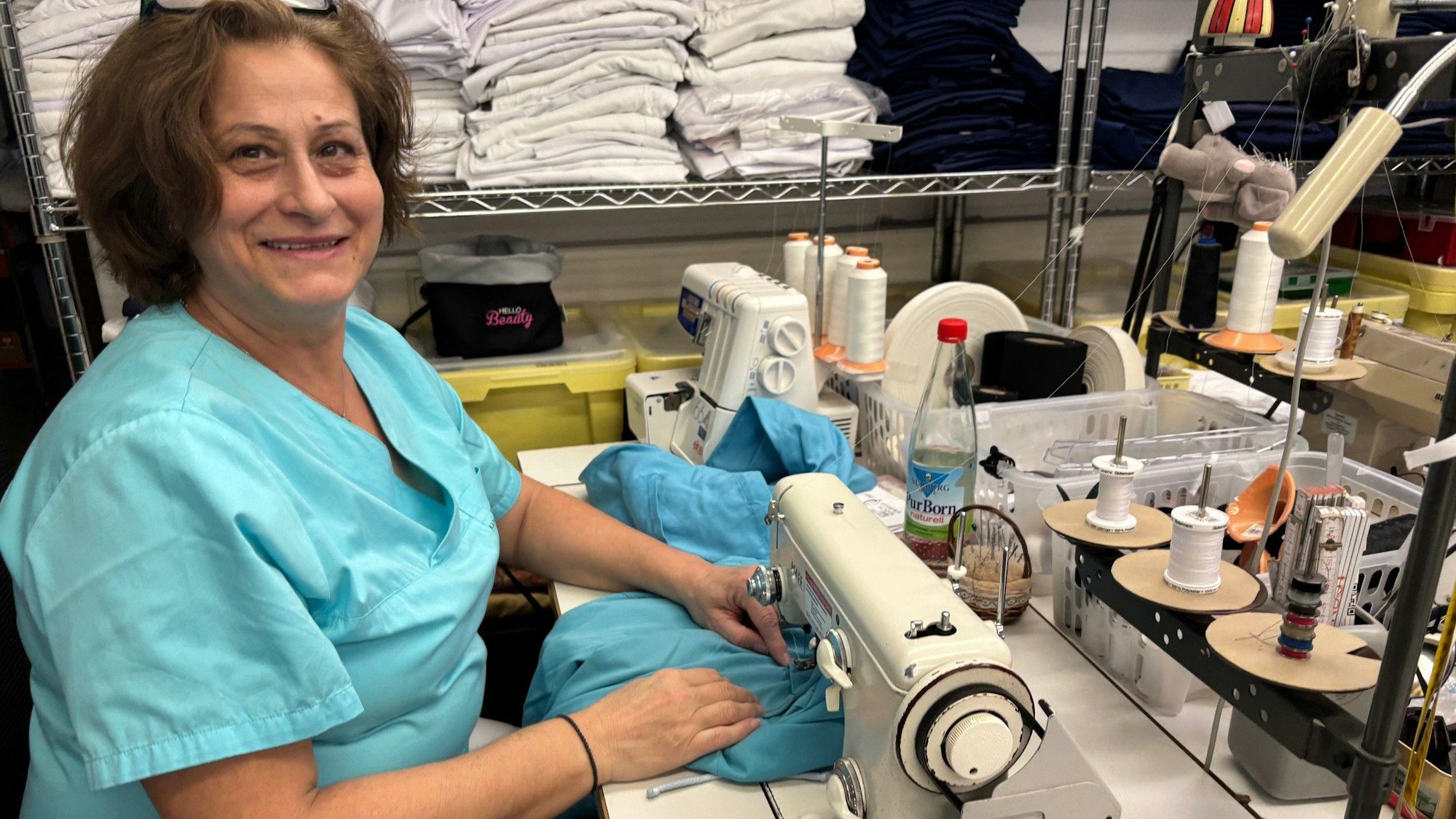 Auf dem Bild ist eine Frau an einer Nähmaschine zu sehen.