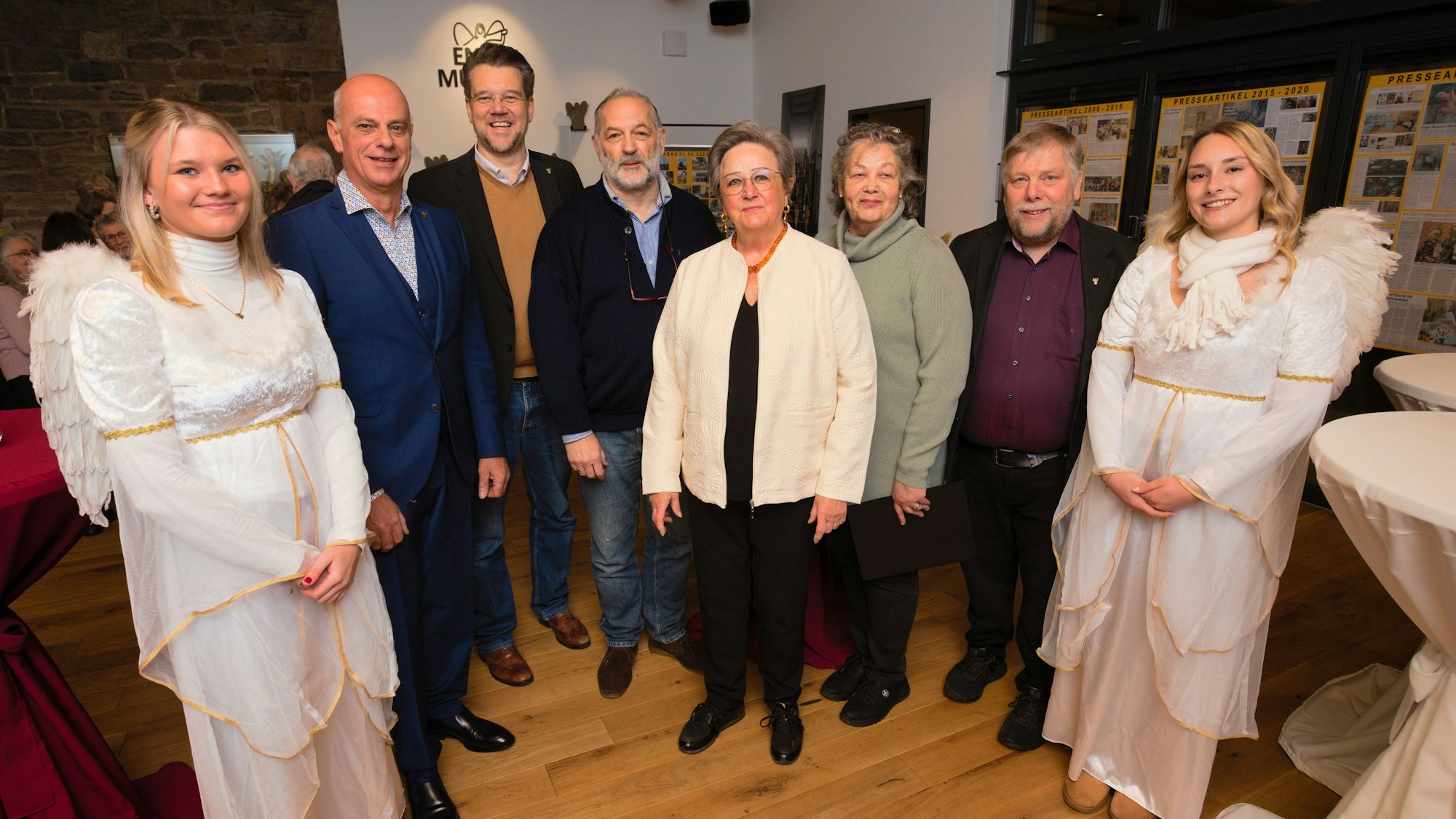 Eine Gruppe, eingerahmt von zwei jungen Frauen im Engelkostüm.