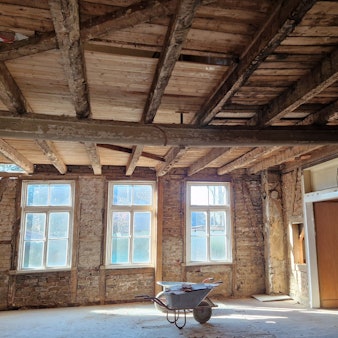 Blick in einen ehemaligen Saal, in dem Wand- und Deckenverkleidungen entfernt wurden.