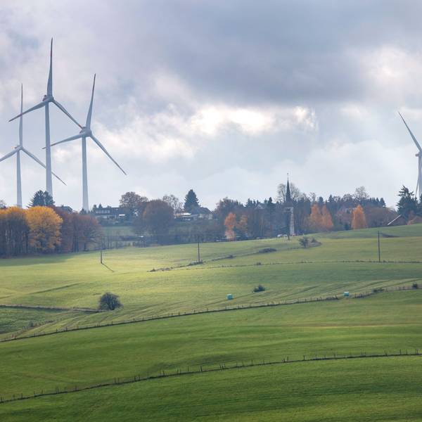 Windräder ragen über die herbstlich gefärbte Landschaft empor.