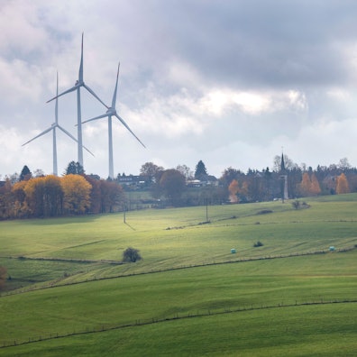 Windräder ragen über die herbstlich gefärbte Landschaft empor.