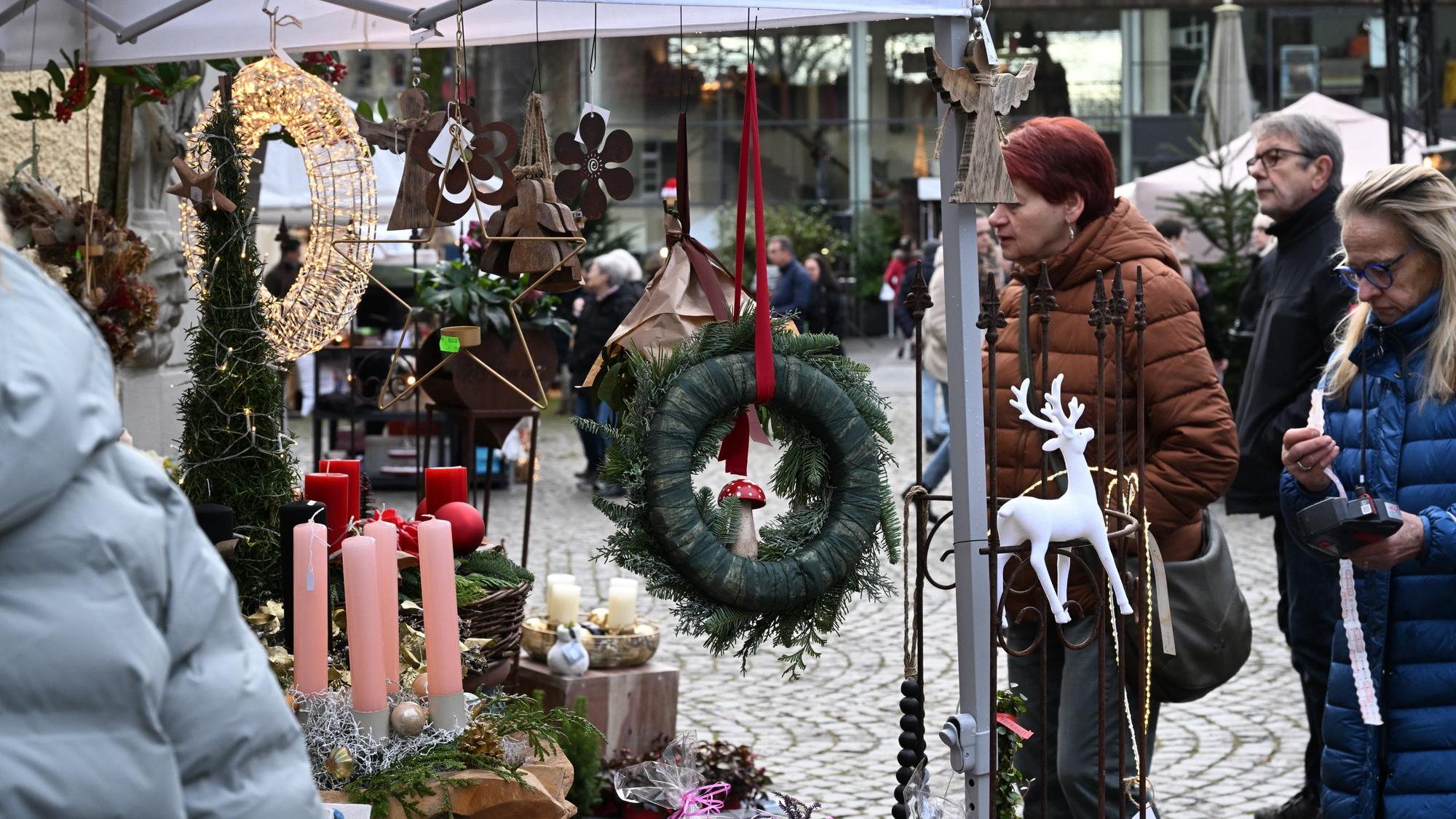 Besucherinnen und Besucher des Weihnachtsmarktes auf Schloss Eulenbroich betrachten Deko-Artikel.