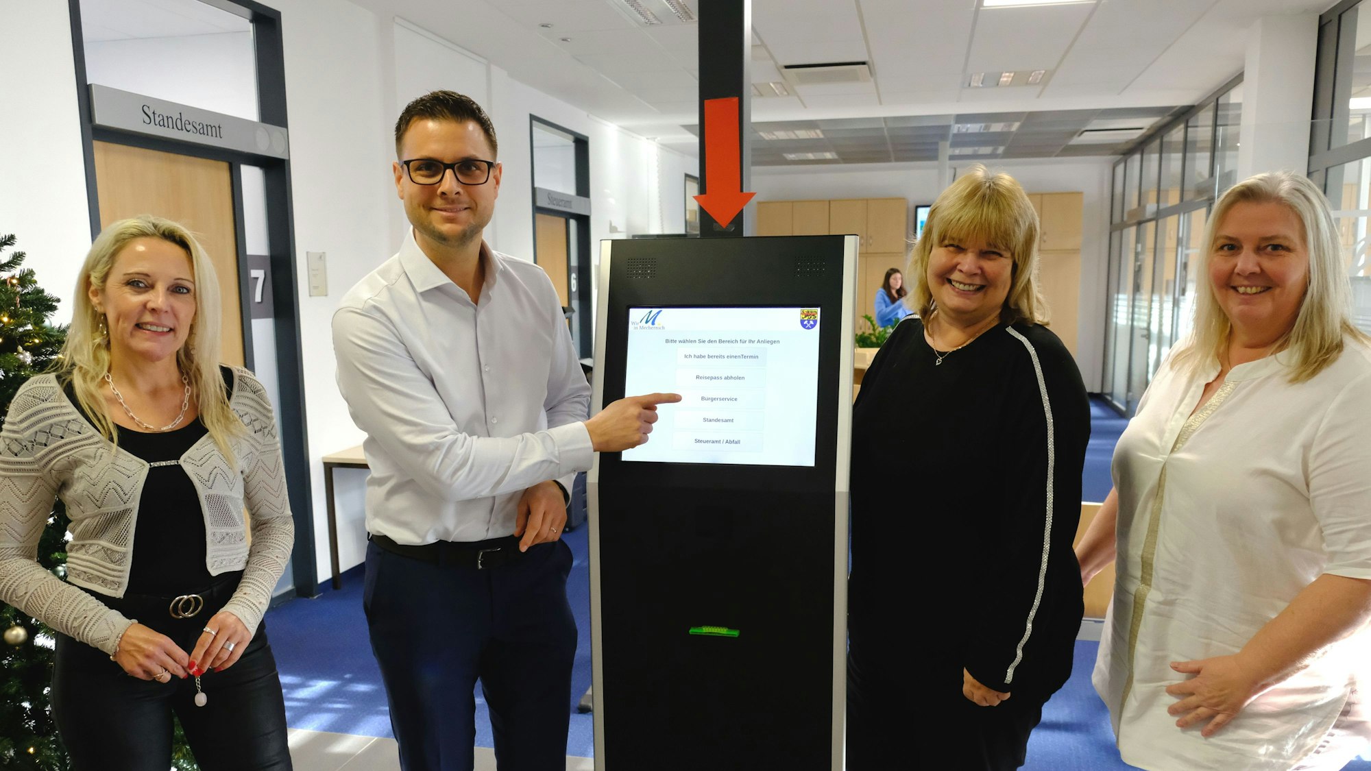 Michael Fingel und drei Mitarbeiterinnen stehen an einem digitalen Bildschirm im Rathaus in Mechernich.