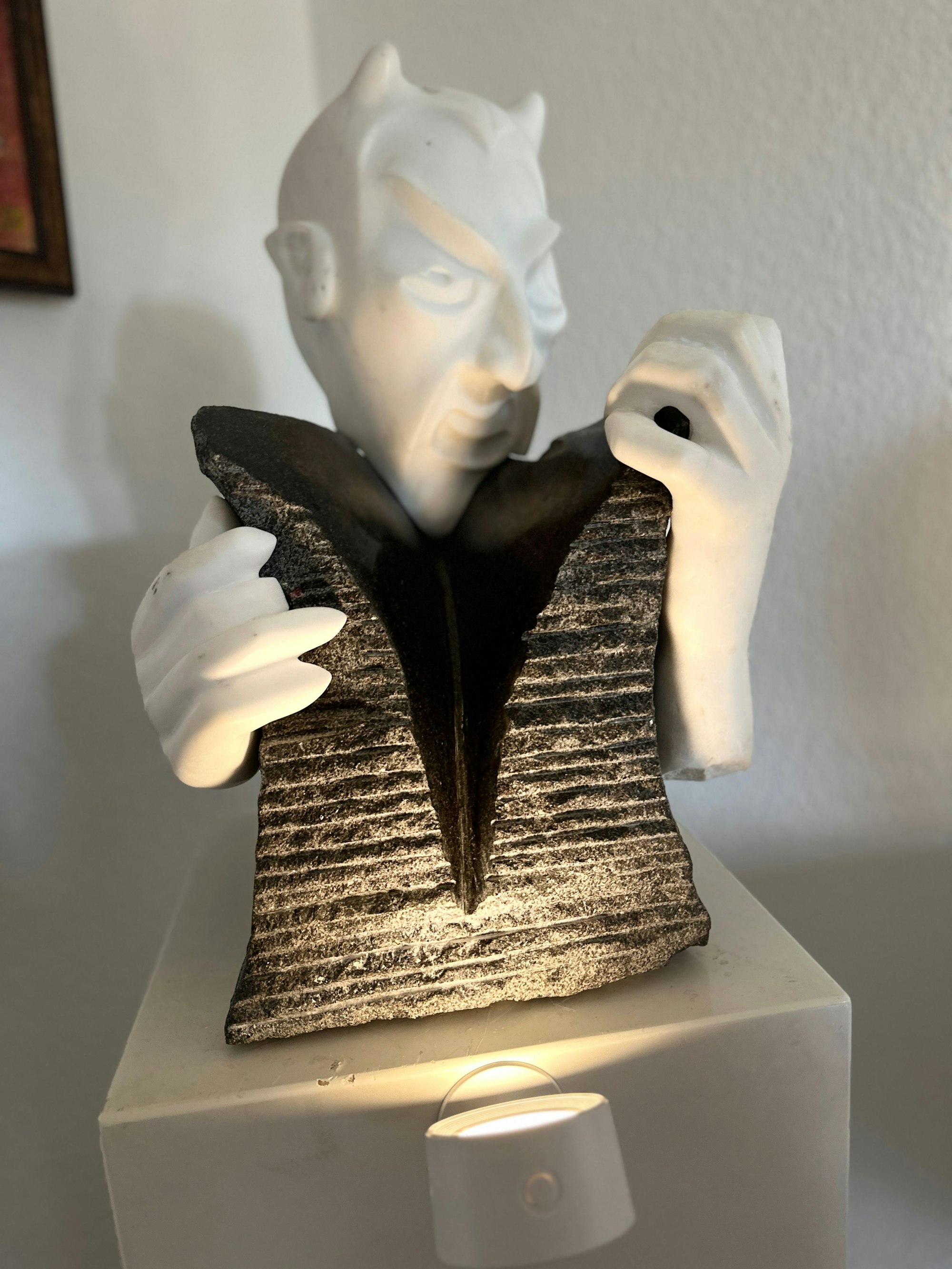 Eine Figur mit Teufelshörnern steht auf einer Säule.