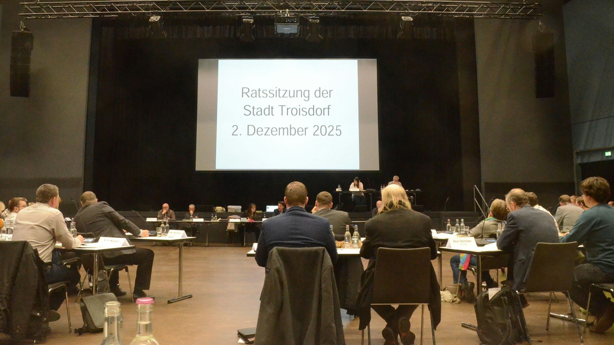 Männer und Frauen in einem Sitzungssaal.