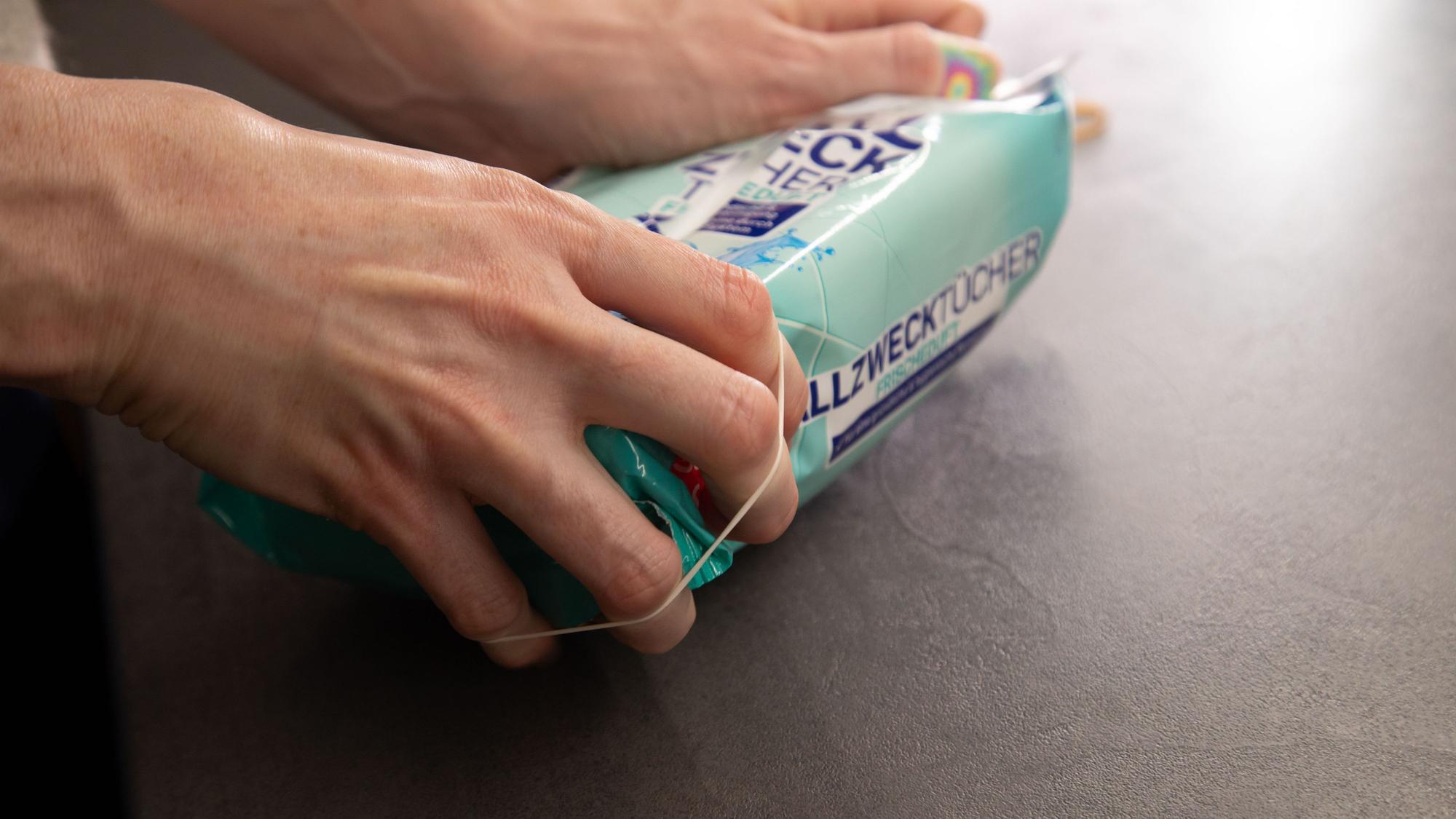 So geht's: Gummibänder links und rechts von der Öffnung der Verpackung anbringen.