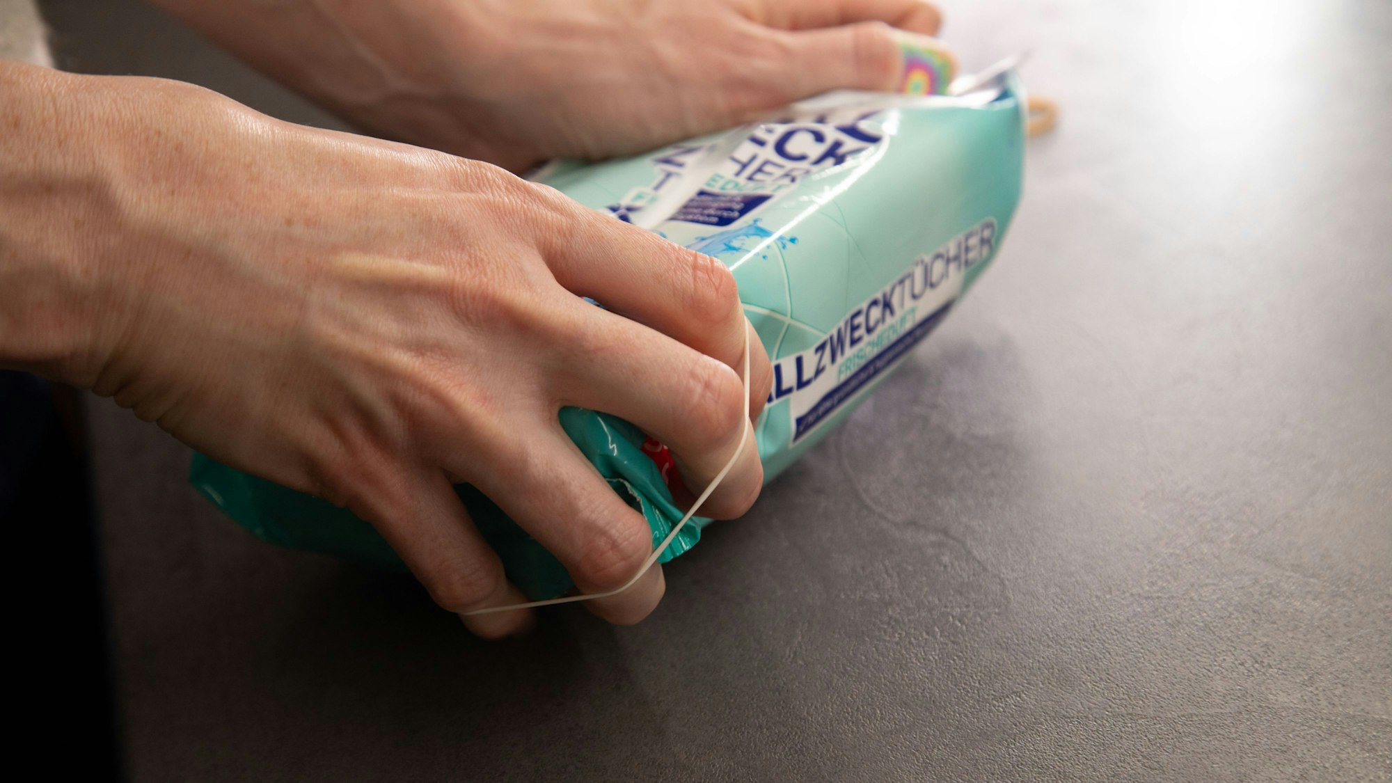 So geht's: Gummibänder links und rechts von der Öffnung der Verpackung anbringen.