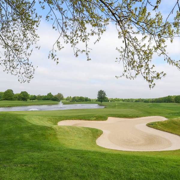 Das Bild zeigt den Golfplatz samt grüner Wiesen und Sandbunkern.