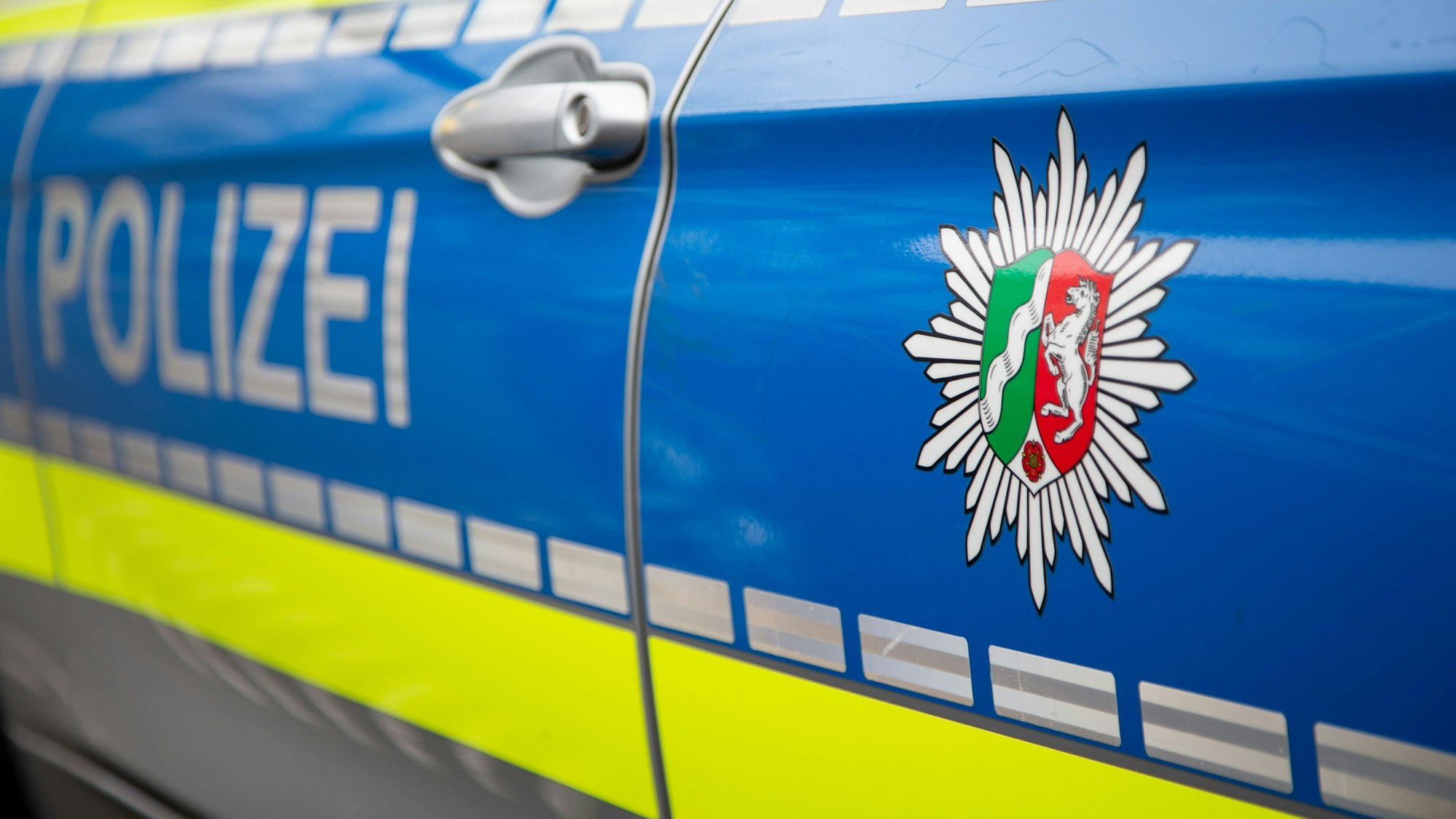 Zu sehen ist ein Emblem der Polizei in NRW an einem Polizeiauto.