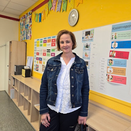 Eine Frau vor einer Pinnwand in der Schule.