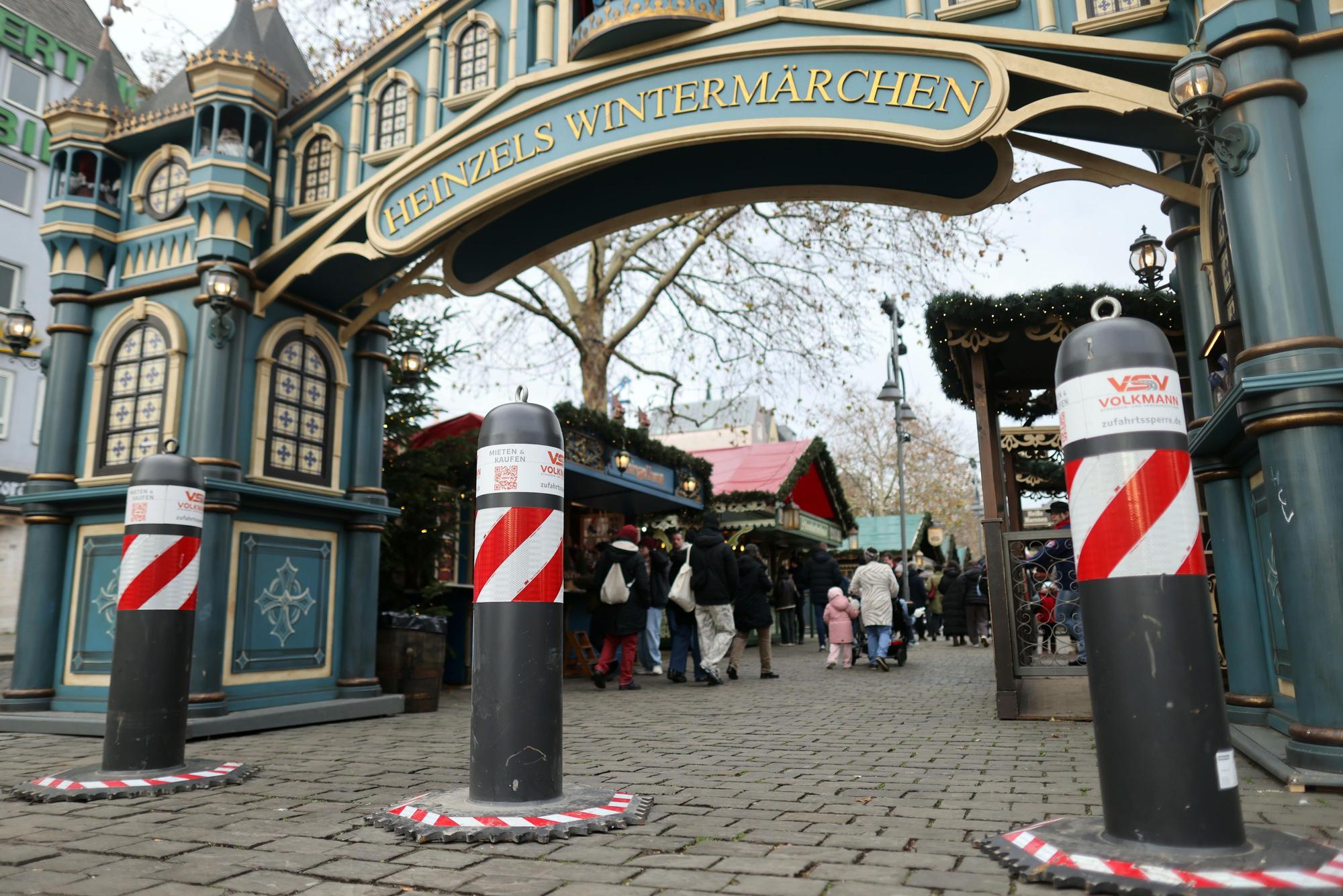Antiterror-Poller stehen vor dem Weihnachtsmarkt „Heinzels Wintermärchen“ auf dem Kölner Heumarkt.