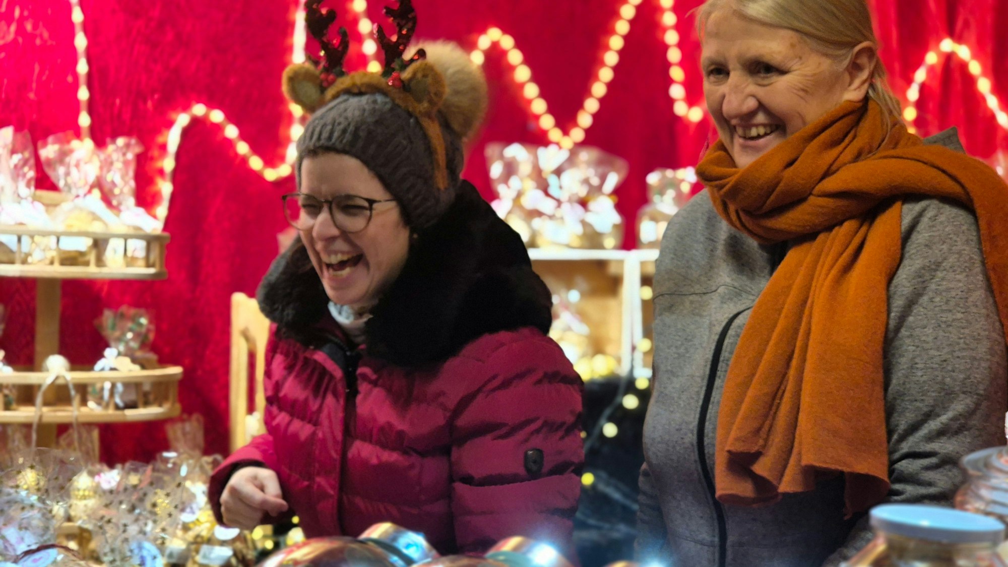 Zwei Frauen in einem Verkaufsstand mit Plätzchen. Eine lacht lauthals.
