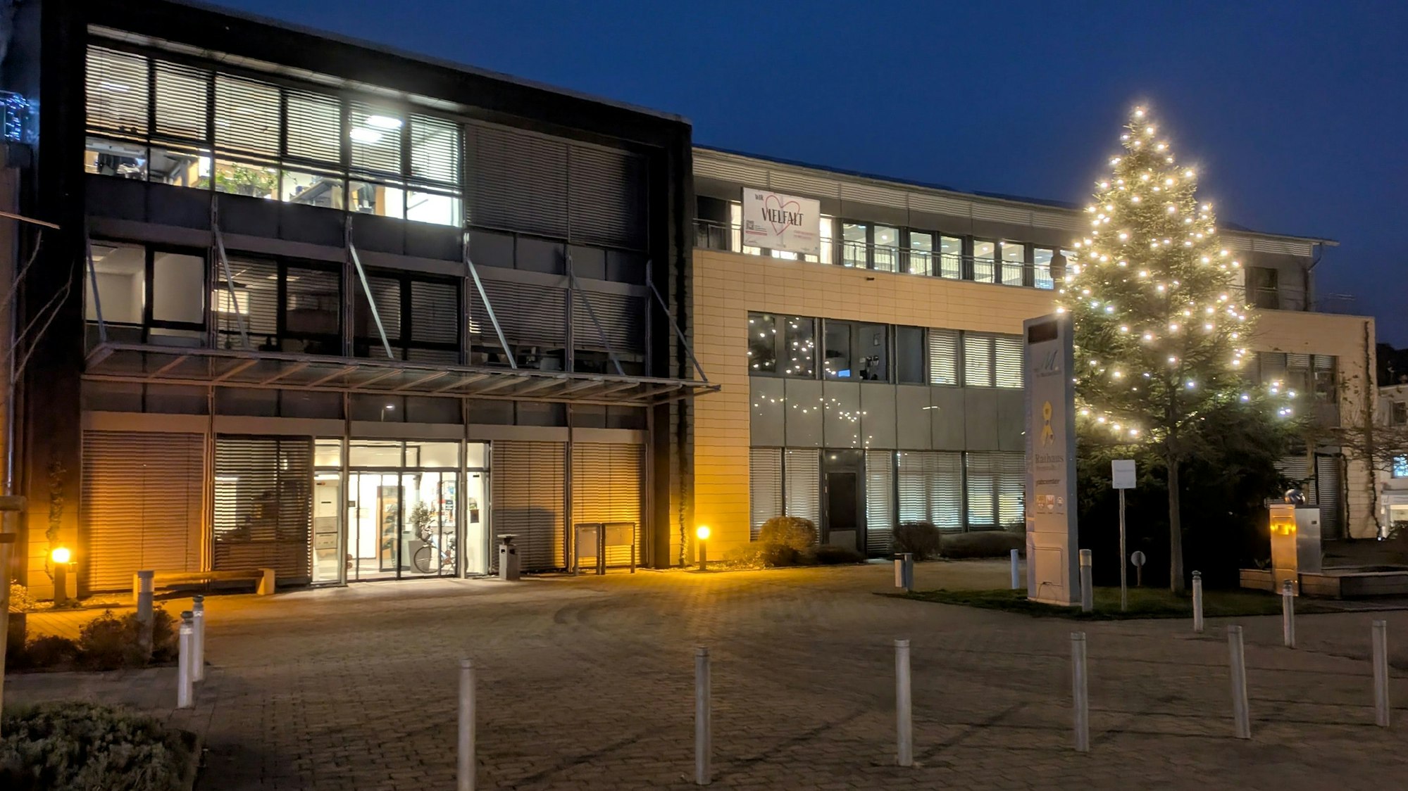 Das Mechernicher Rathaus in der Adventszeit: In der Abenddämmerung leuchtet ein mit Lichterketten geschmückter Weihnachtsbaum vor dem Verwaltungsgebäude.