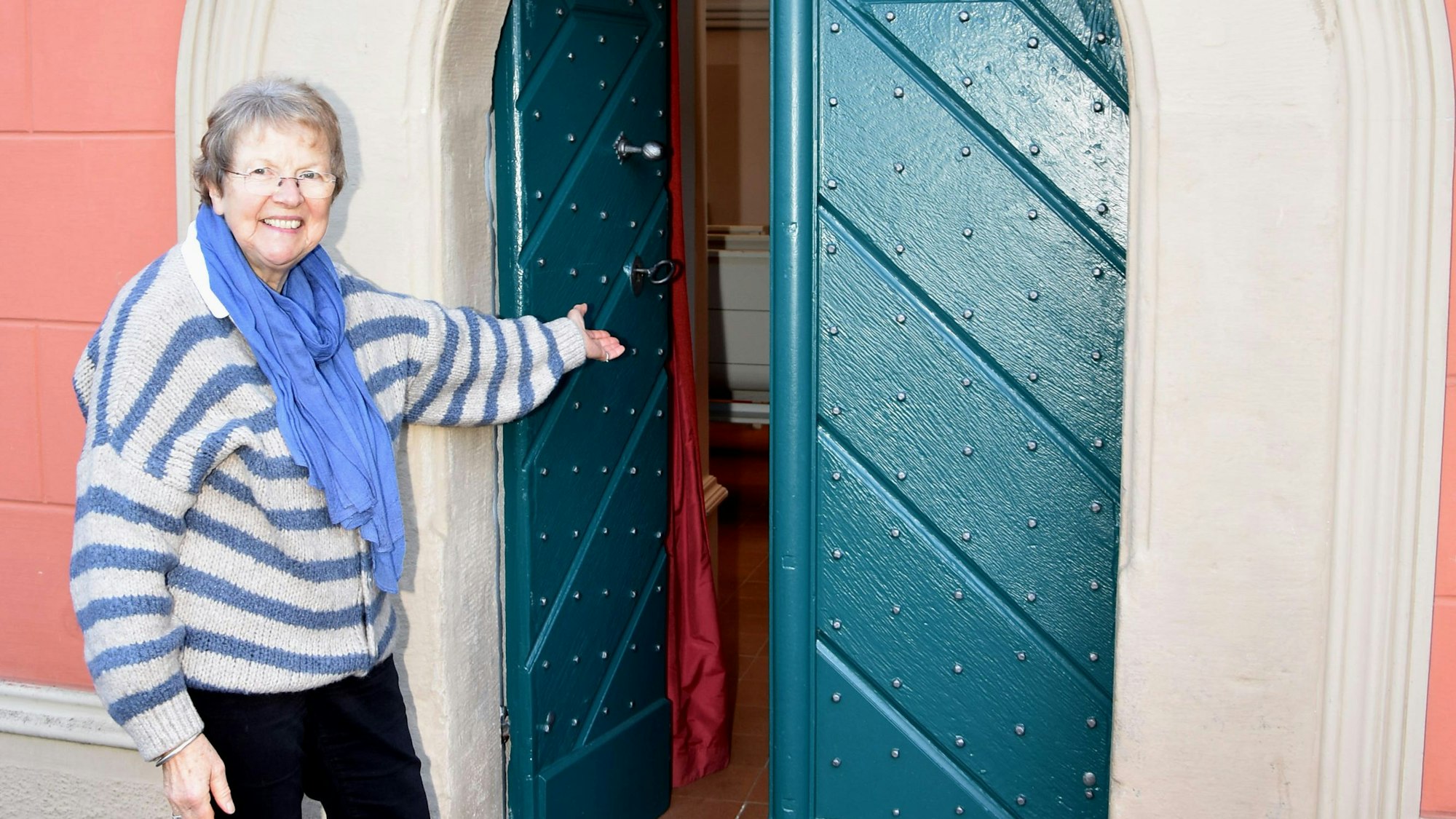 Das Foto zeigt eine Frau, die die Tür zu einer Hauskirche öffnet.