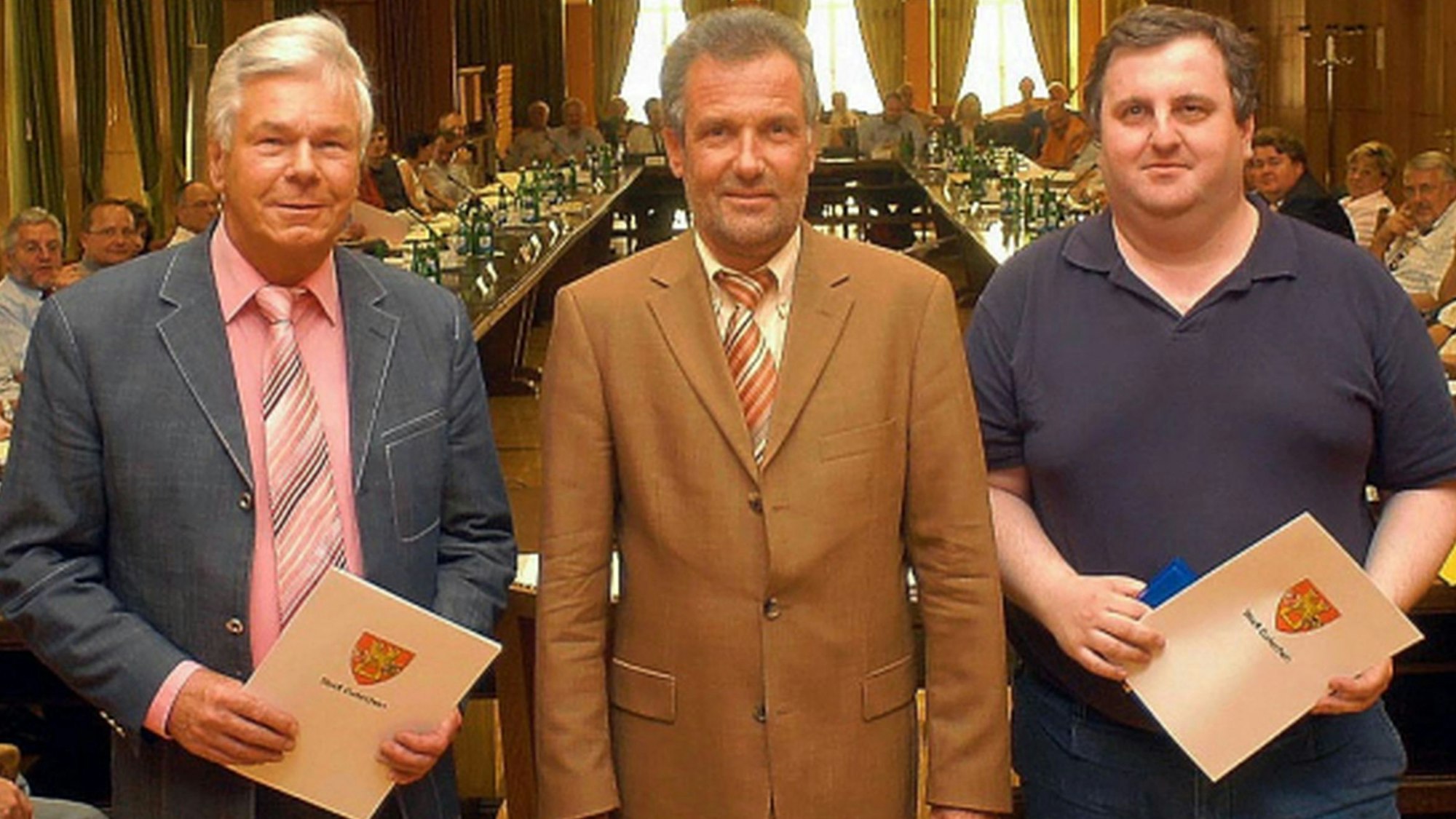 Ulf Schlüter und Guido Bachem, jeweils mit Urkunden, flankieren den Bürgermeister.