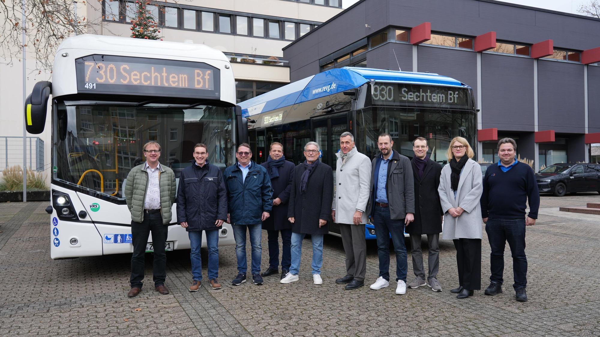 Die Vertreter der Städte, der Kreise und der Verkehrsunternehmen stehen vor zwei Linienbussen.