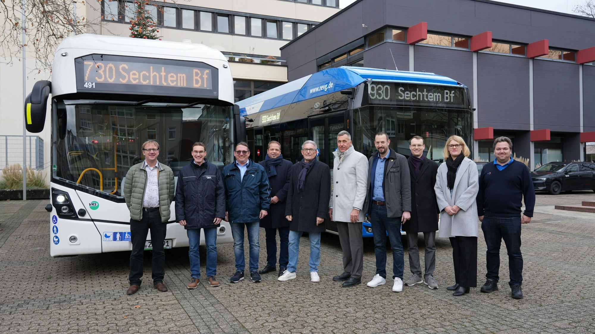 Die Vertreter der Städte, der Kreise und der Verkehrsunternehmen stehen vor zwei Linienbussen.