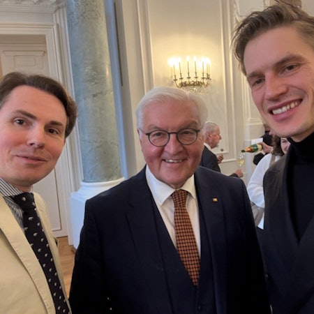 Die drei Männer lächeln in die Kamera.