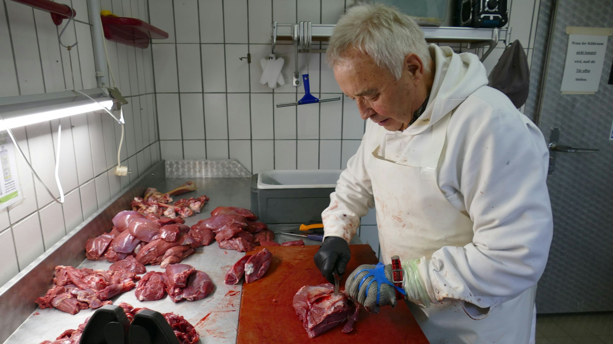 Ein Mann zerlegt Fleischstücke.