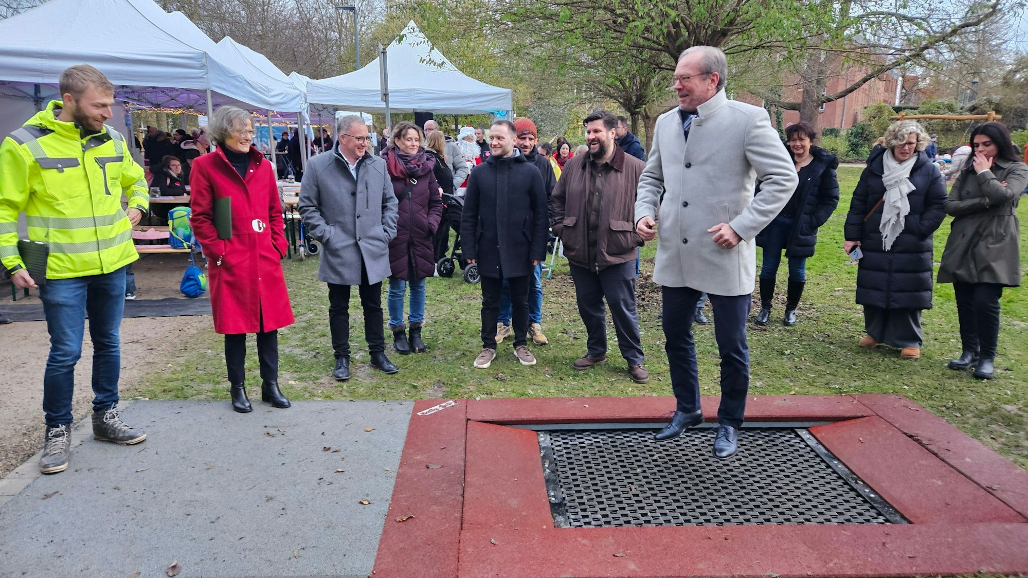 Zu sehen ist ein Mann auf einem Trampolin, um ihn herum stehen mehrere Menschen.