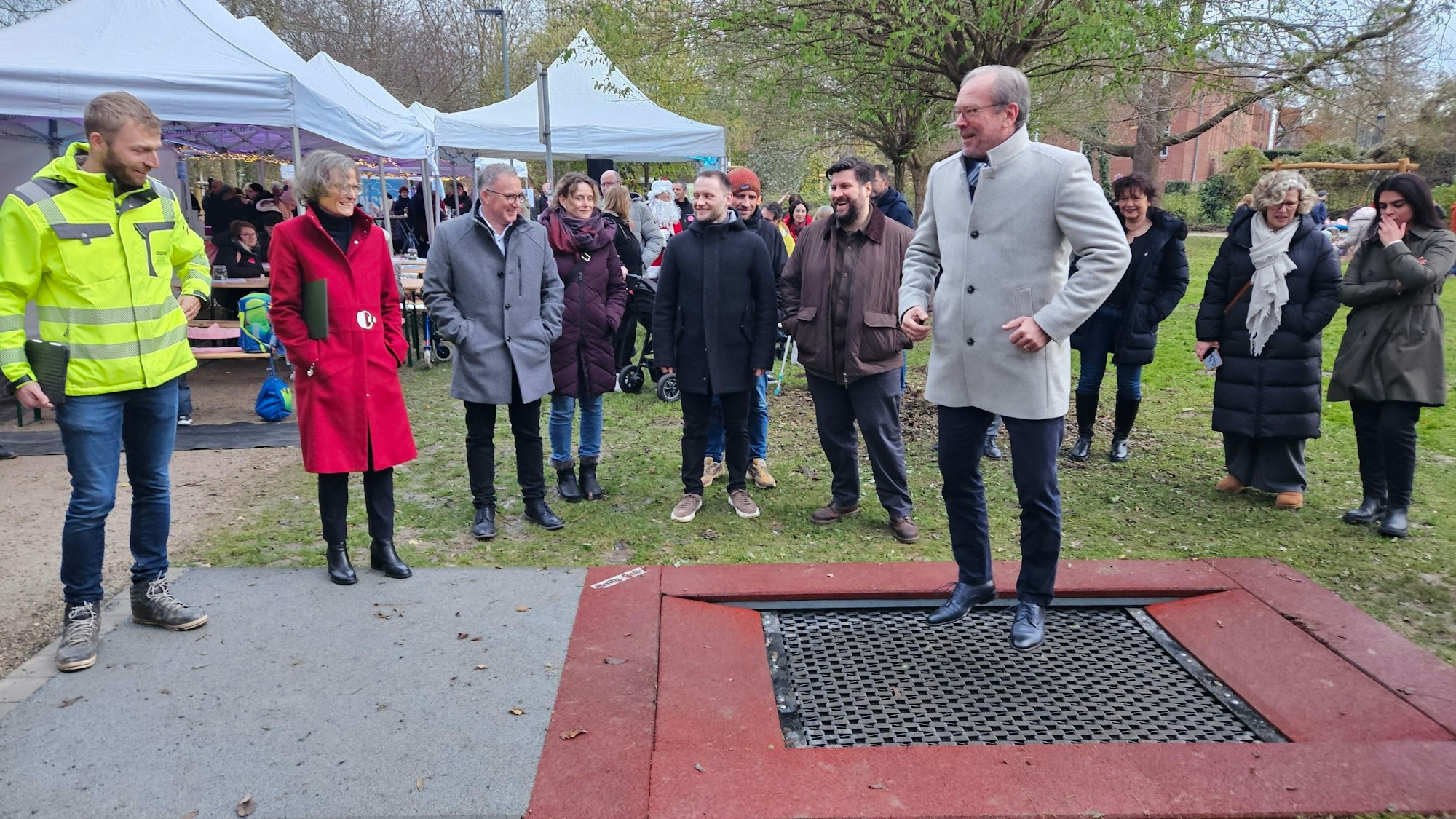Zu sehen ist ein Mann auf einem Trampolin, um ihn herum stehen mehrere Menschen.