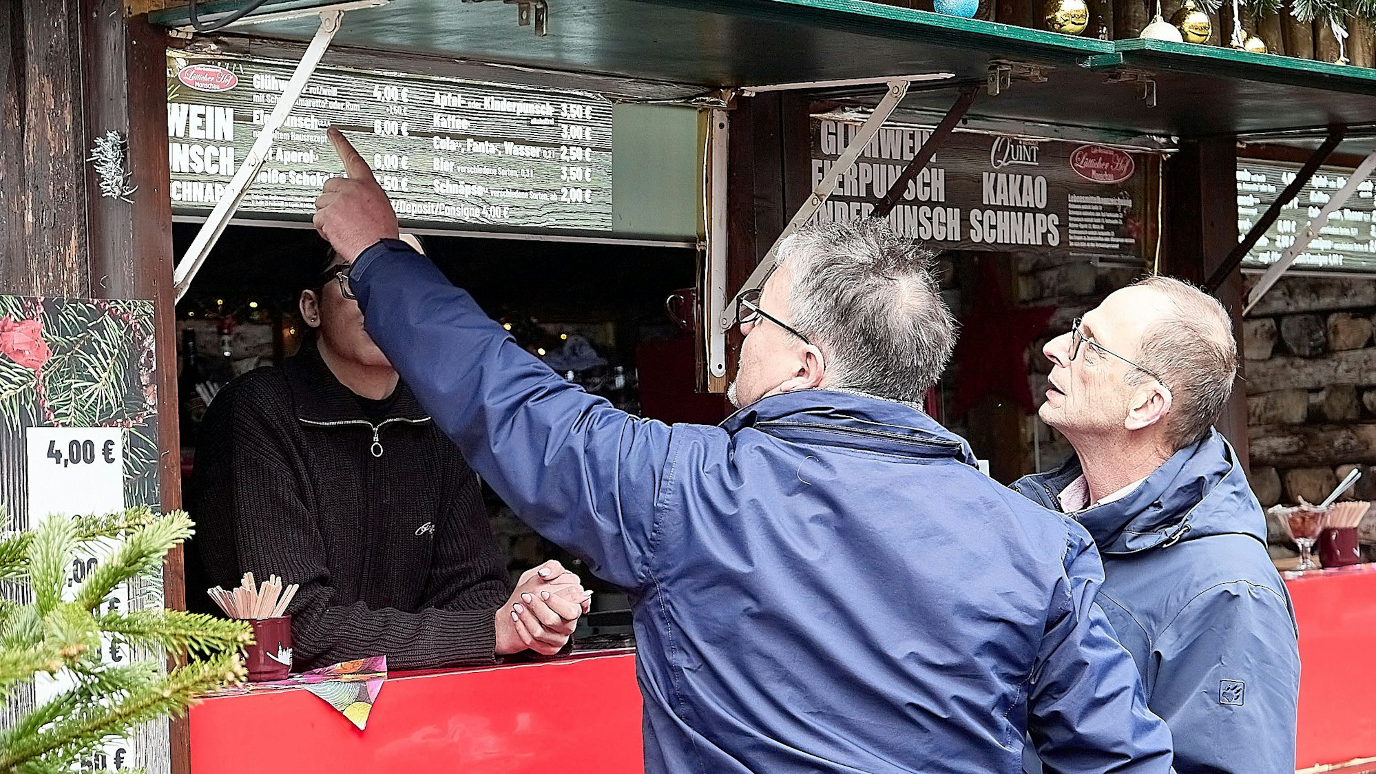 Zwei Lebensmittelkontrolleure stehen an einer Glühweinbude auf dem Weihnachtsmarkt in Monschau, die sie überprüfen werden.