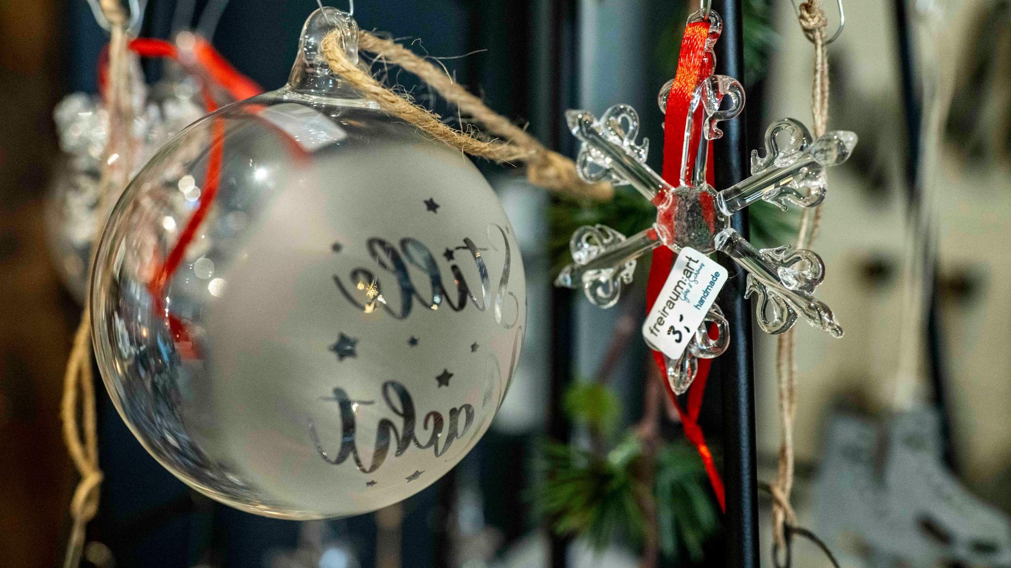 Das Bild zeigt eine gläsene Weihnachtskugel und einen Weihnachtsstern aus Glas.