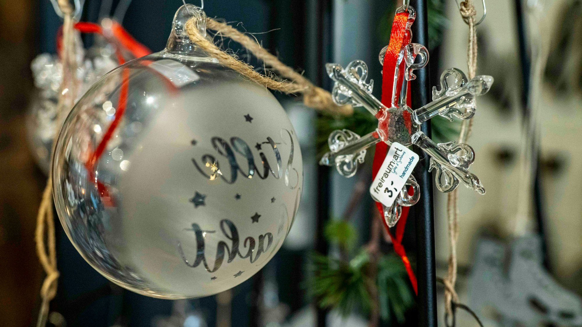 Das Bild zeigt eine gläsene Weihnachtskugel und einen Weihnachtsstern aus Glas.