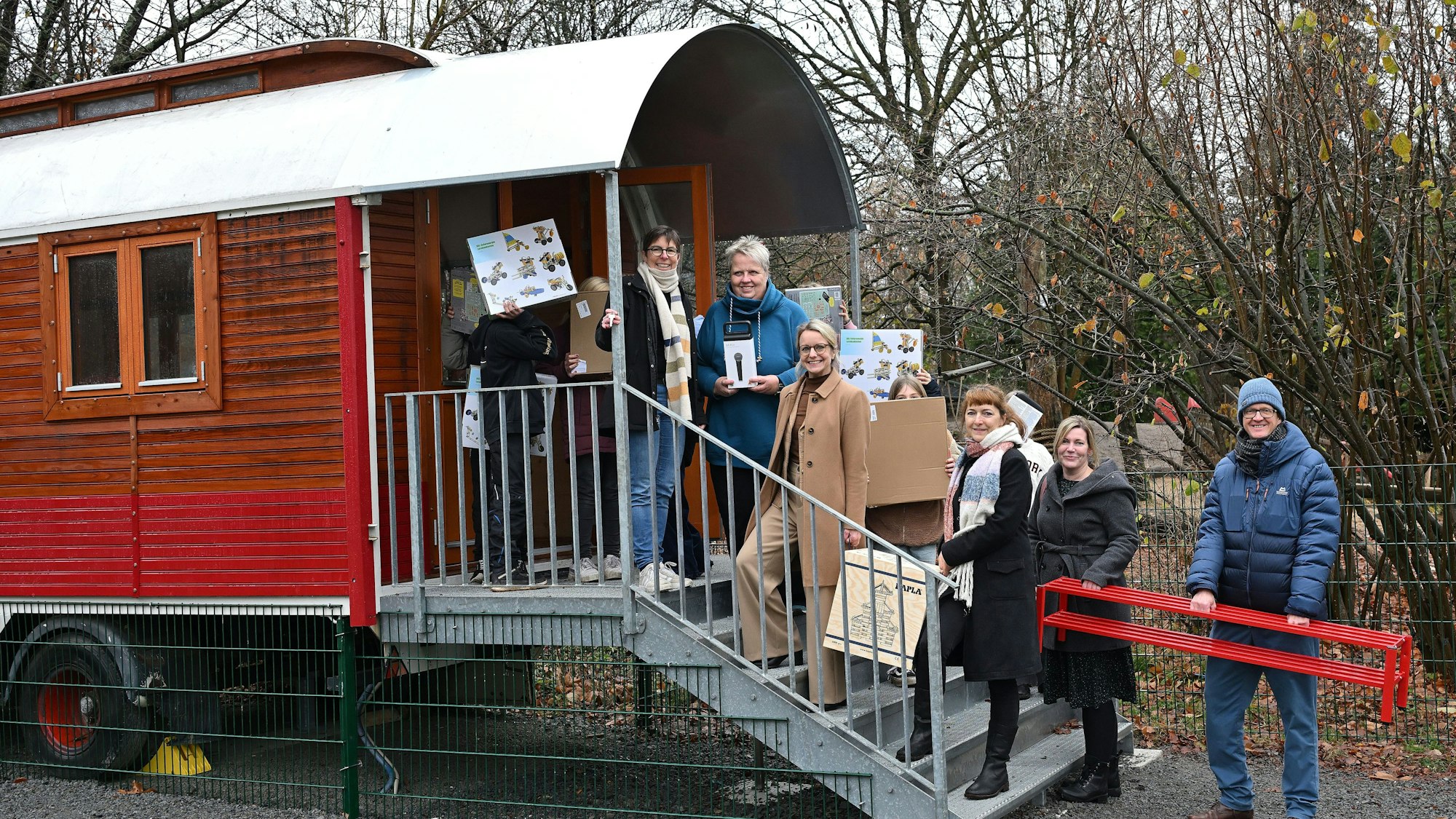 Ein umgebauter Zirkuswagen mit Treppe, darauf stehen viele Menschen.