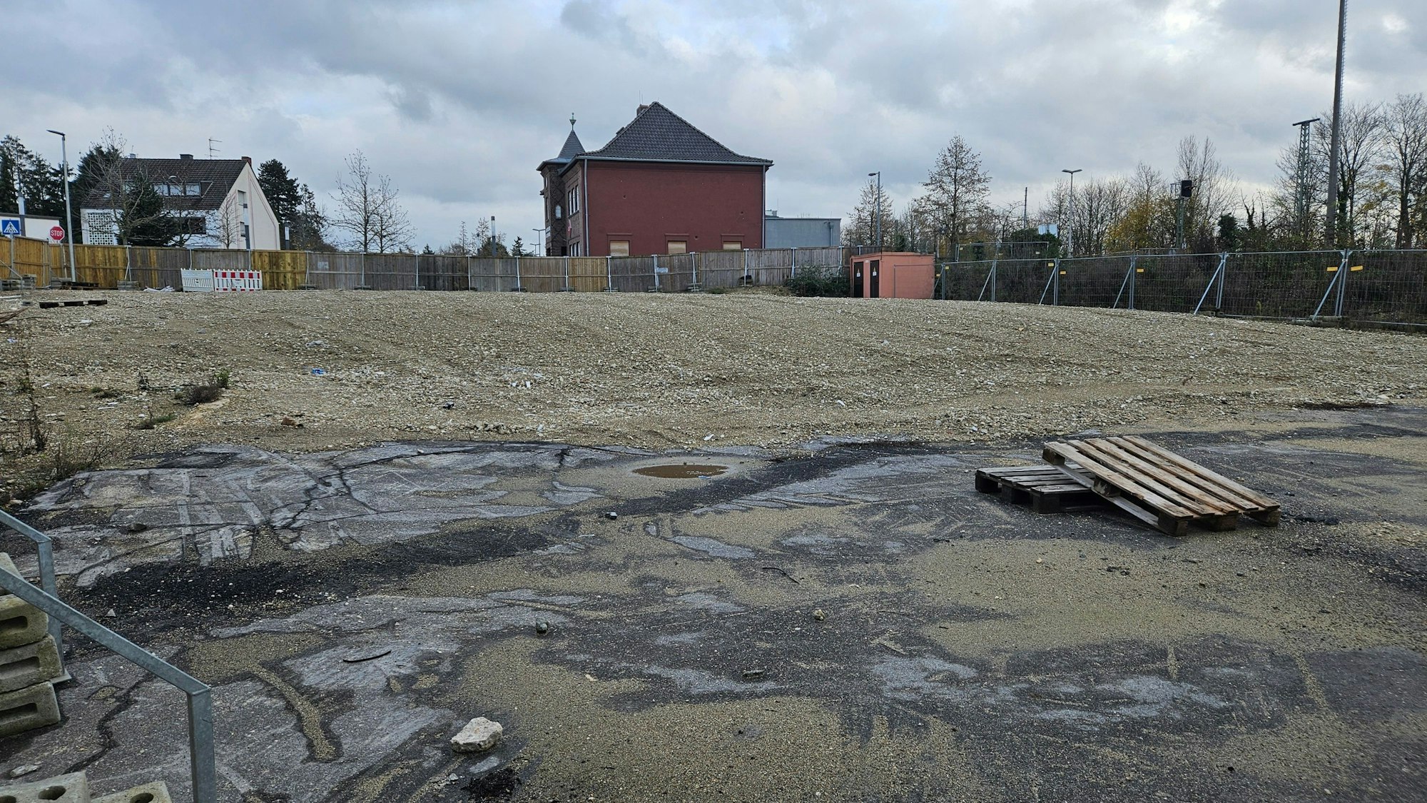 Zu sehen ist ein brachliegendes Grundstück hinter einem Bauzaun.