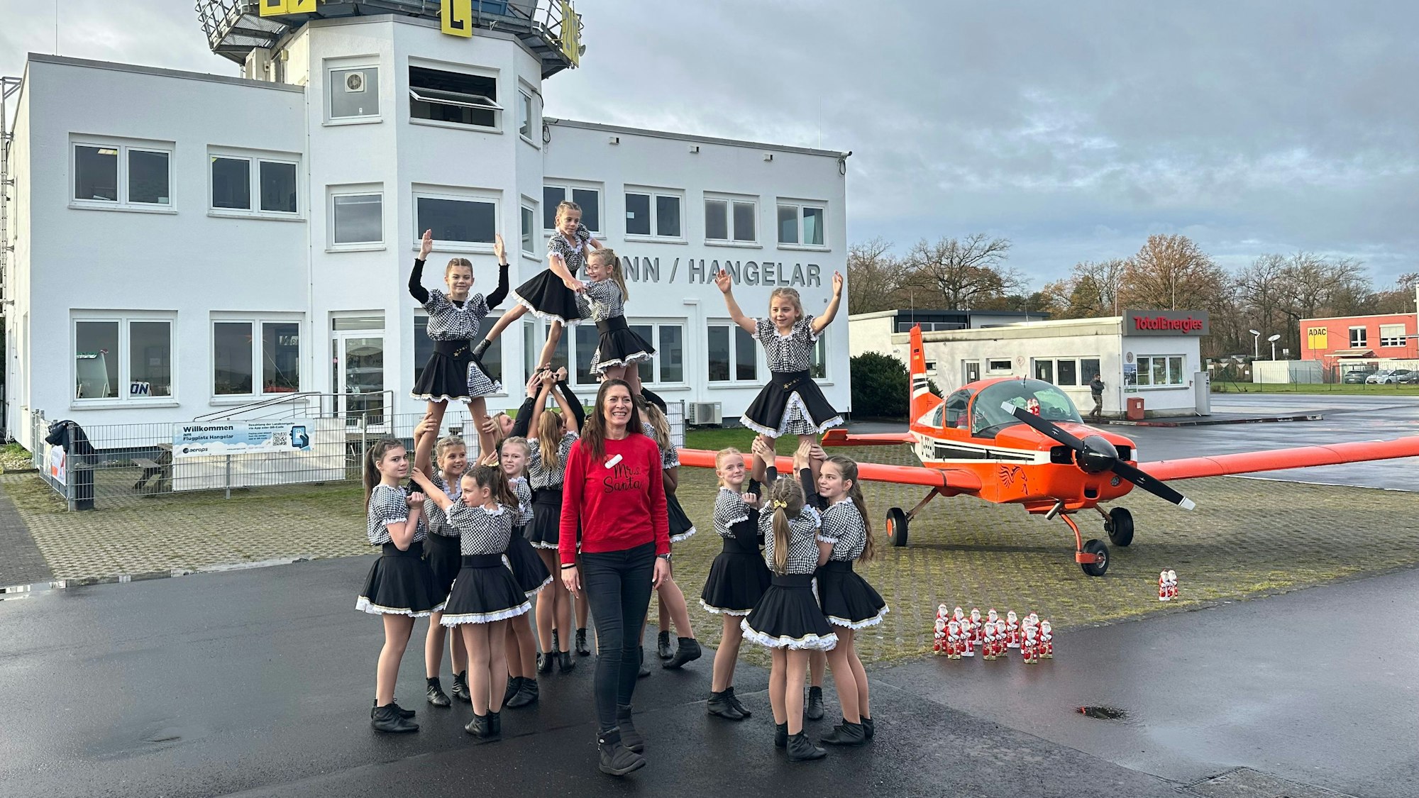 Eine Tanzfigur vor dem Tower des Flugplatzes präsentieren die Karnevalistinnen der „Stääneflejer“, in der Mitte Organisatorin Kathrin Kaiser.