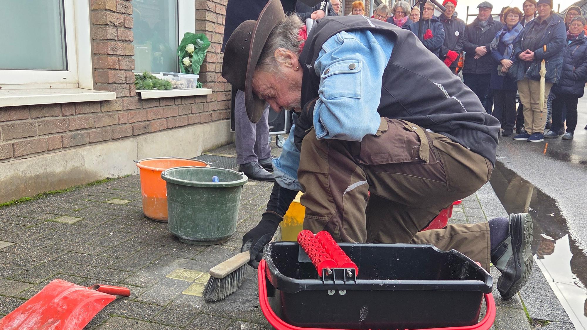 Gunter Demnig, Initiaor des Stolpersteine-Projekts in Deutschland, setzt die drei ersten Stolpersteine von Spich in den Asphalt ein.