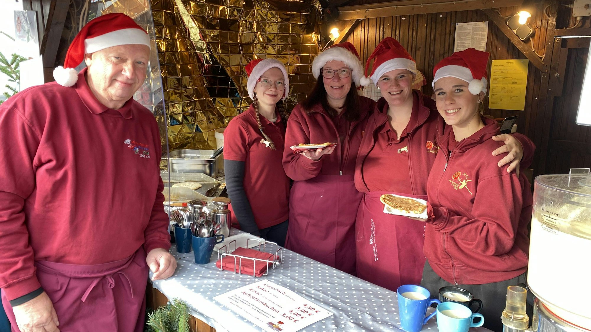 Mitglieder des Prinzen Clubs stehen mit Nikolausmützen an ihrem Waffelstand.