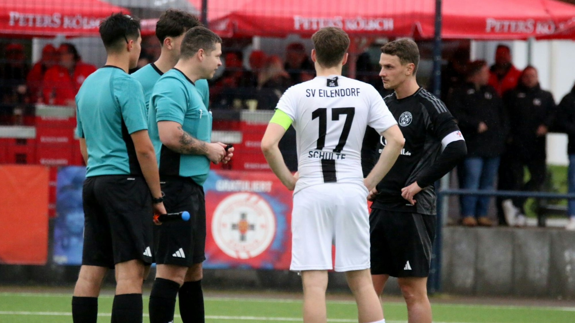 Das Schiedsrichtergespann hat die beiden Kapitäne zu sich gerufen und spricht mit ihnen.
