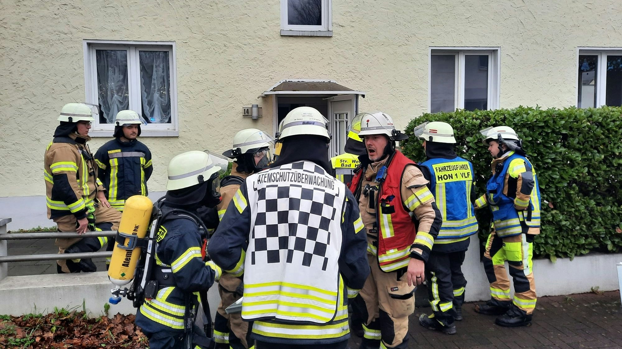 Feuerwehrleute vor einem Mehrfamilienhaus.